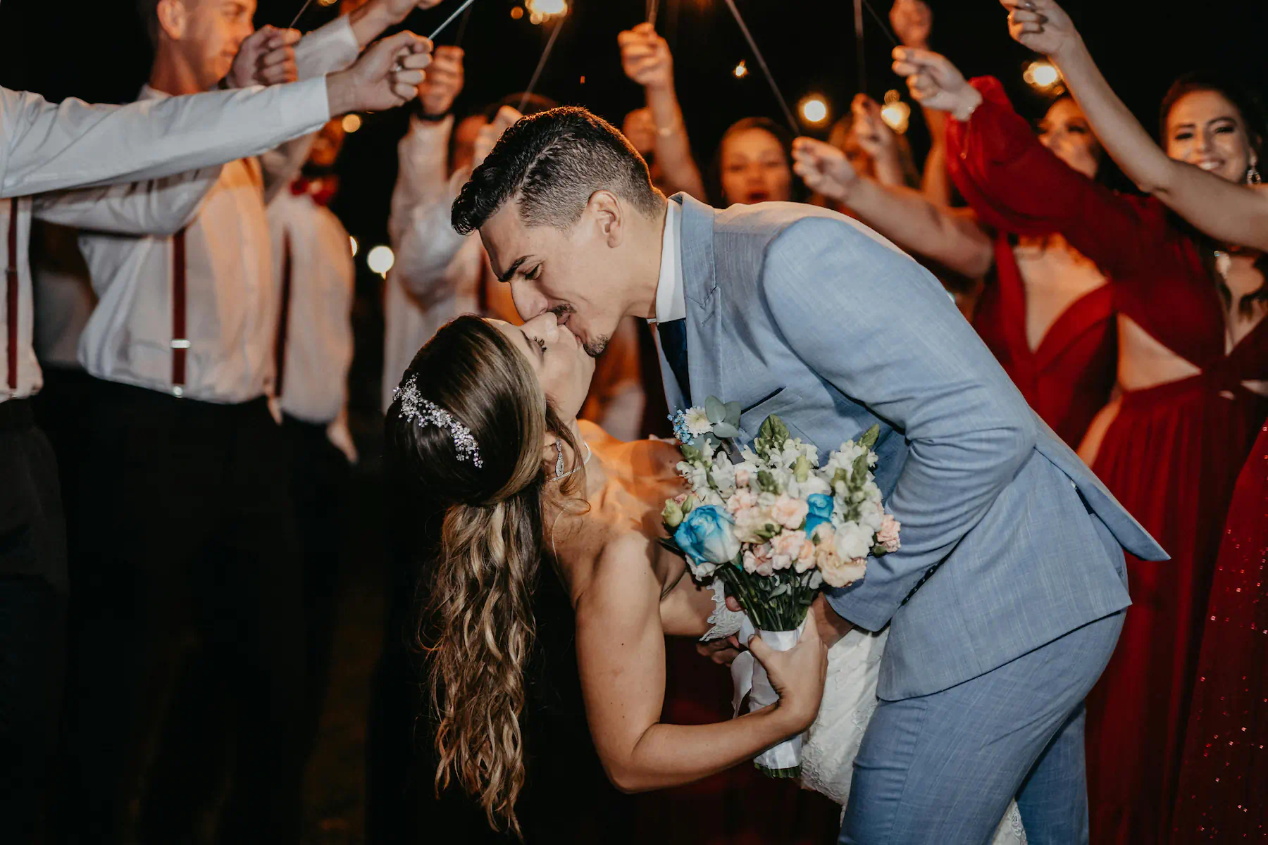 Wedding couple sharing a dramatic dance-floor kiss while guests celebrate around them