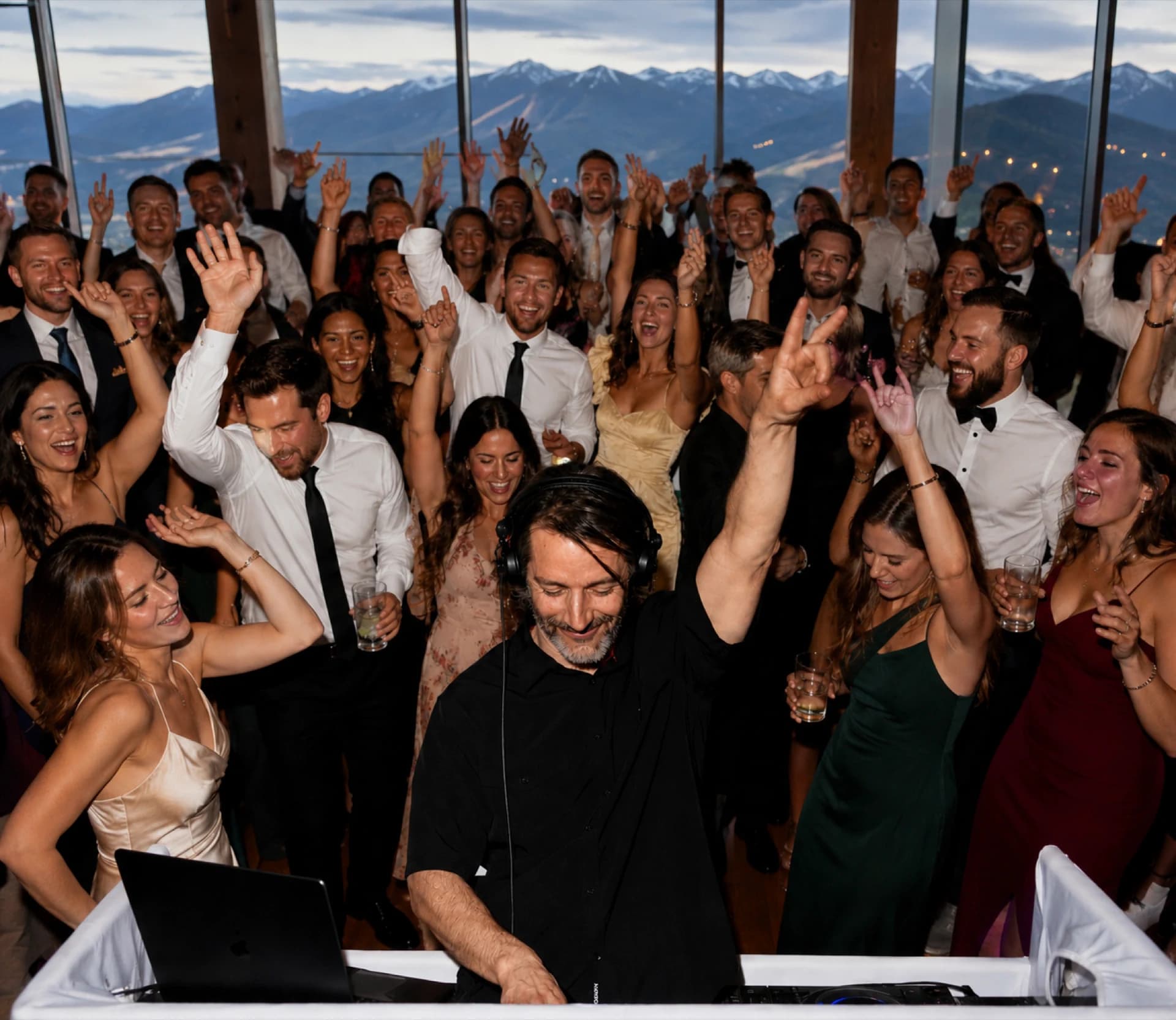 Wedding guests celebrating on a packed dance floor with a mountain backdrop through large windows