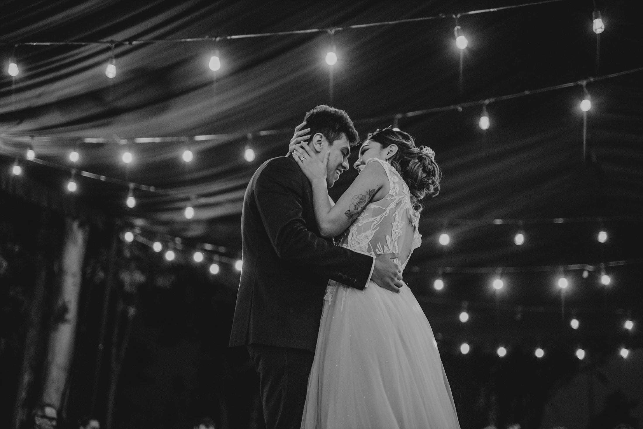 Newlyweds sharing a first dance beneath string lights